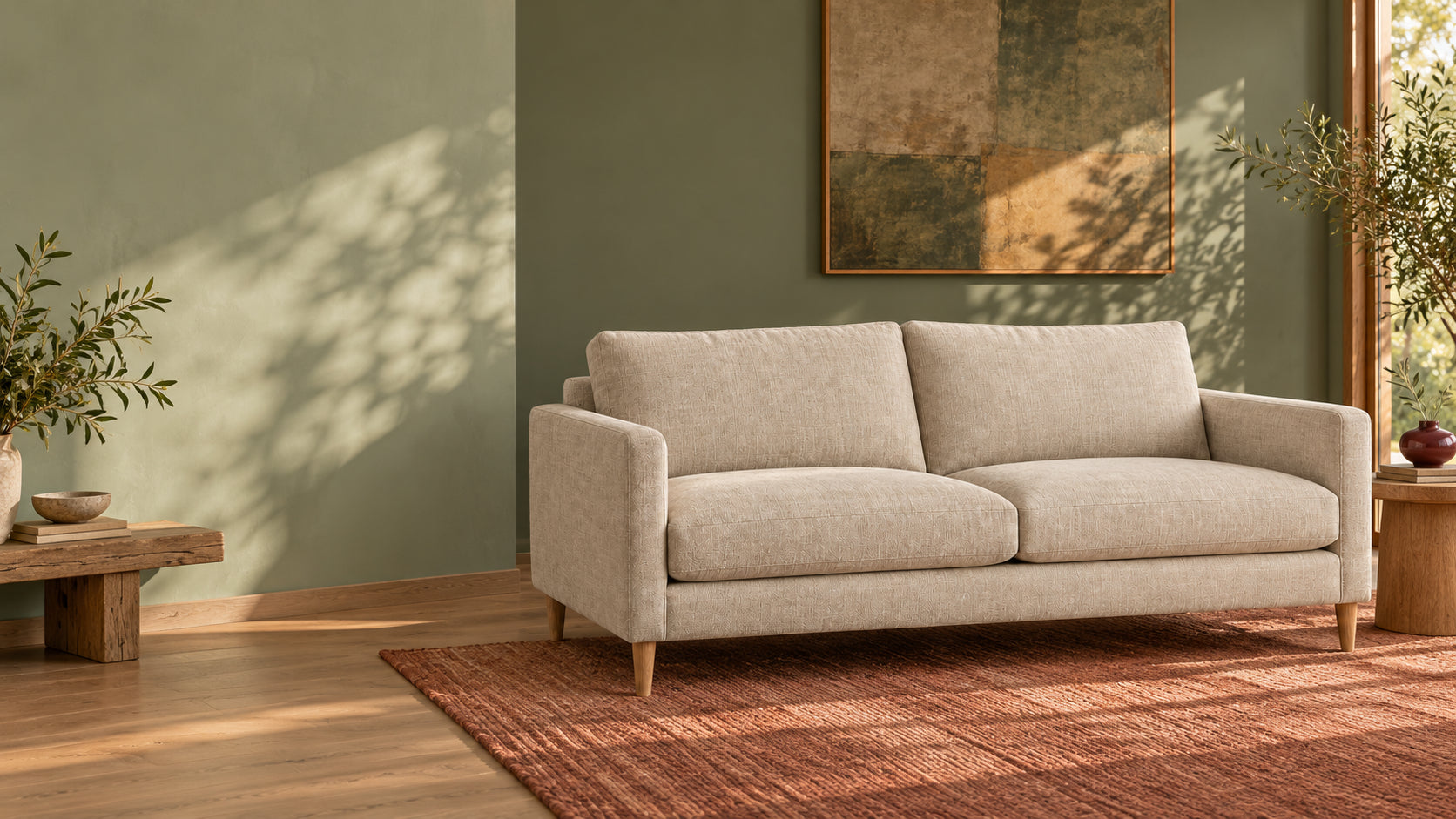 Illustrative room with sage walls, an oat sofa and terracotta rug